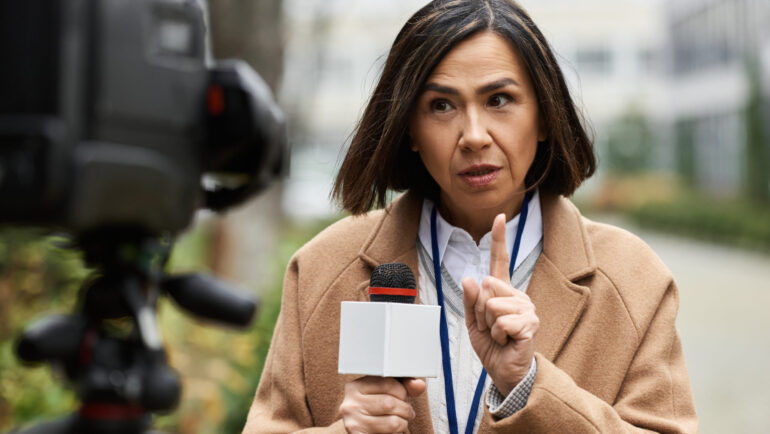 A talented journalist holds a microphone and engages audiences while reporting news outdoors.